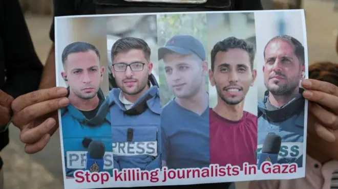 A poster is held up showing the images of five Al Jazeera journalists killed in Gaza.
