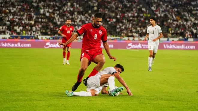 المدافع العراقي يحاول استخلاص الكرة أمام المهاجم الأردني علي علوان