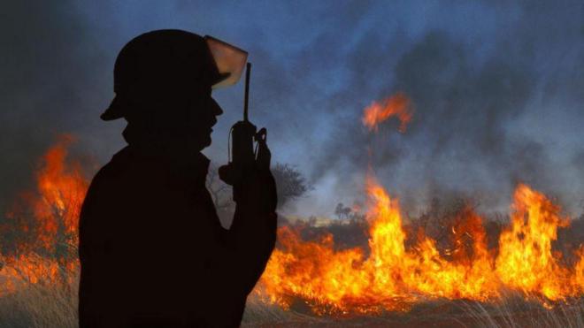 Bombeiro com incêndio ao fundo