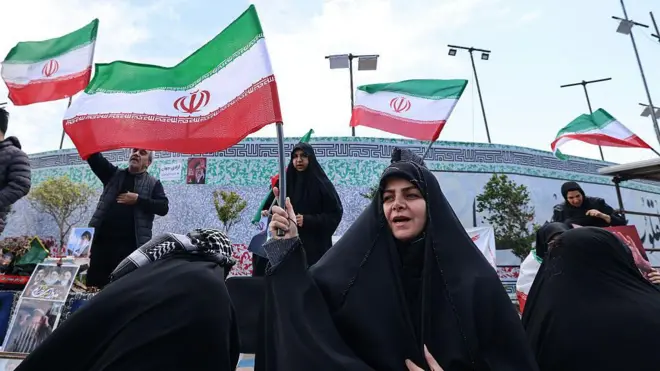 Mujeres iraníes ondean banderas nacionales mientras la gente se reúne en la Plaza de la Revolución de Teherán después de que Estados Unidos e Irán acordaran un alto el fuego de dos semanas.