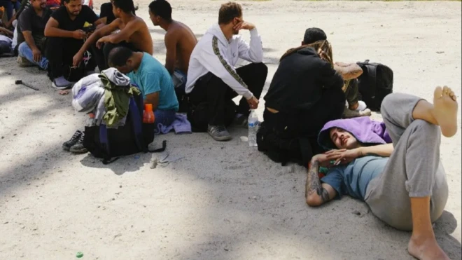 مهاجرون يجلسون على الأرض