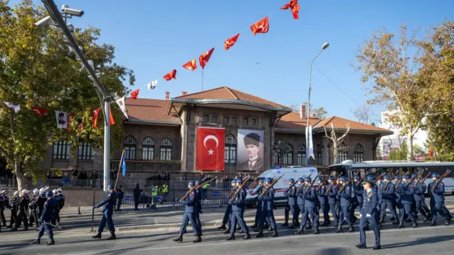 Askerler Birinci Meclis binasının önünde yürüyor. Binada türk bayrağı ve Atatürk resmi asılı