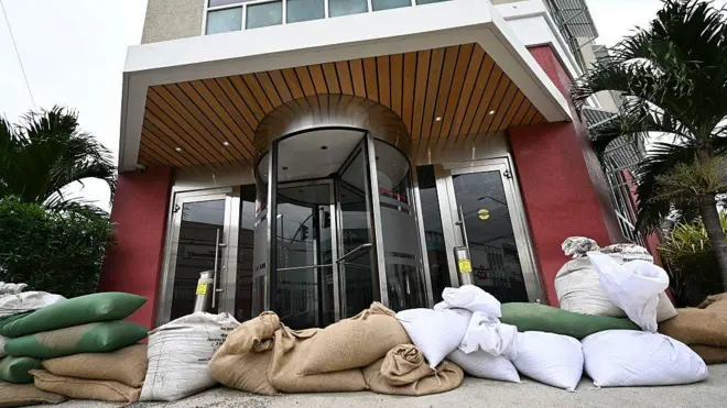 Dem place sandbags for di entrance of di Grace Kennedy building in preparation for di arrival of Hurricane Melissa in downtown Kingston, Jamaica, on October 25, 2025.