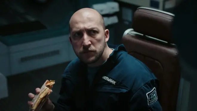 Чоловік їсть бутерброд 