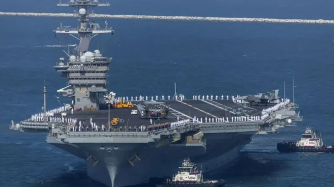 یک ناو بزرگ آمریکایی با خدمه روی عرشه و دو کشتی در اطرافش