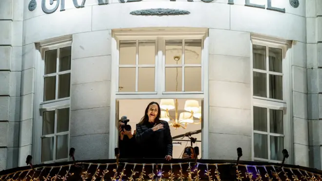 خانم ماچادو شب گذشته پس از ماه‌ها مخفی بودن برای اولین بار در شهر اسلو، پایتخت نروژ برای طرفدارانش از بالکن یک هتل دست تکان داد