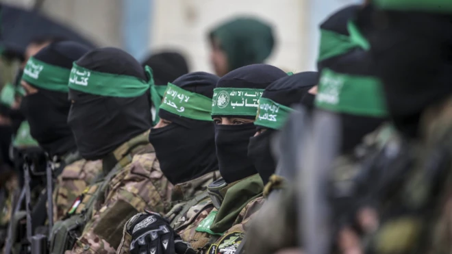 Armed fighters from Hamas' Izz ad-Din al-Qassam Brigades stand guard during the handover of three Israeli hostages to Red Cross representatives in Al Nuseirat refugee camp, central Gaza Strip,