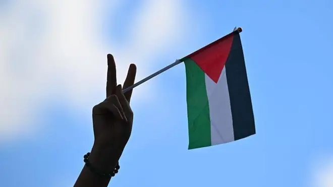 Рука з палестинським прапорцем на фоні неба