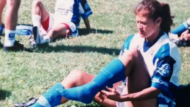 Guerrero sentada en la grama arreglándose las medias 