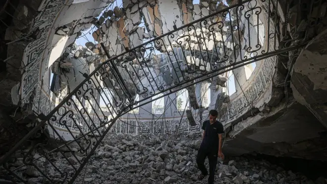 The inside of the destroyed Khalid Bin Al-Waleed mosque. A man is observing the damage from inside the dome