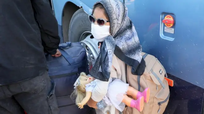 دختر مهاجر افغان عروسکی در دست دارد