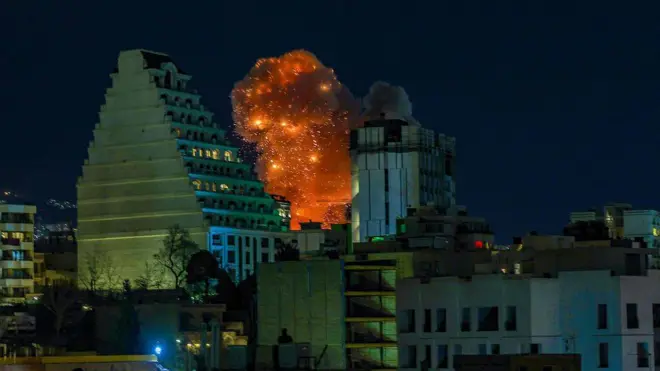 Uma grande coluna de fumaça se eleva sobre Teerã após relatos de explosões na cidade durante a noite de 7 de março.