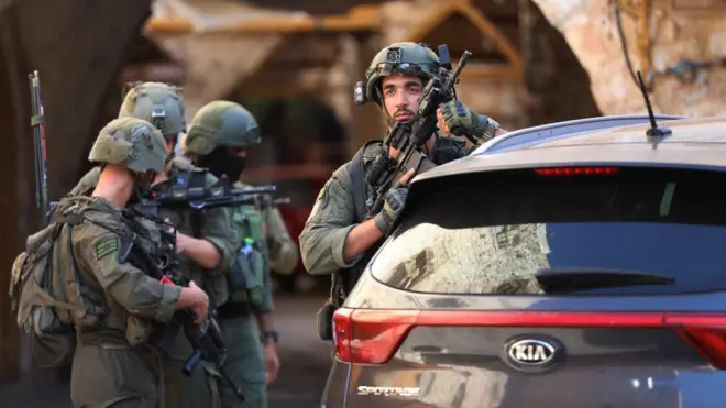 17 अगस्त 2024 की इस तस्वीर में वेस्ट बैंक के हेब्रॉन एक यहूदी बस्ती की सुरक्षा करते इसराइली सैनिक