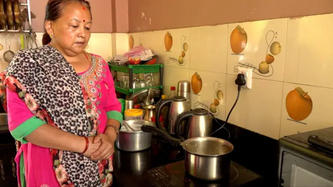 इन्डक्शन चुलोमा चिया पकाउँदै गरेकी महिला