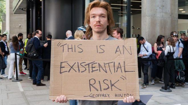 Londra'da Geoffrey Hinton'ın sözleriyle, "Varoluşsal bir risk var" pankartı tutan protestocu
