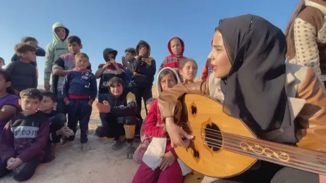 رؤيا حسونة وهي تعزف العود للأطفال في مخيم في رفح