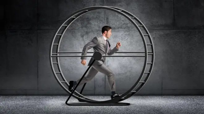 Homem de terno e gravata correndo em uma roda de hamster gigante