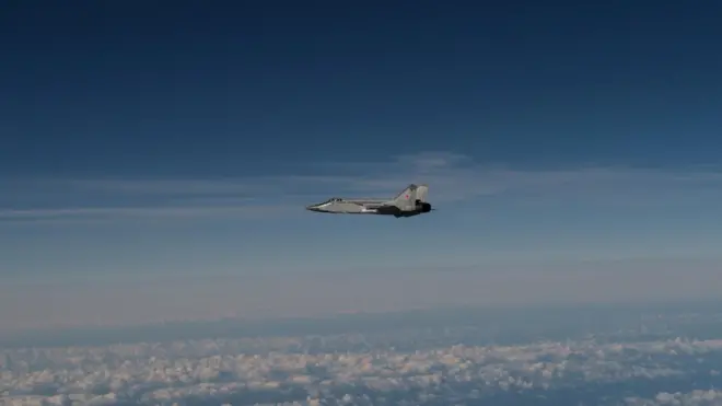 Сірий літак з червоними зірками у ясному небі над хмарами