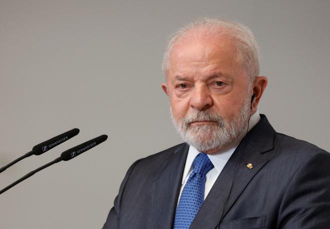 Lula em frente a microfone com fones de ouvido, para receber tradução simultânea, com olhar concentrado