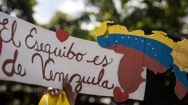 Una persona sostiene un cartel que dice "El Esequibo pertenece a Venezuela" mientras participa en una manifestación en apoyo al referéndum consultivo sobre El Esequibo en Caracas.