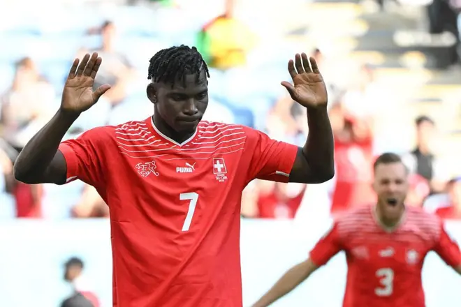 Breel Embolo of Switzerland, wearing a red shirt with the number seven on it, raises his arms after scoring against Cameroon, his country of birth, in the 2022 World Cup