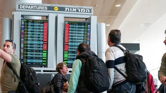المسافرون ينظرون إلى شاشة تعرض الرحلات الجوية المتأخرة بعد تعليق الإقلاع كجزء من الاحتجاجات على مستوى البلاد ضد خطة الإصلاح القضائي للحكومة، وفقا لمتحدث باسم المطار (ليس في الصورة)، في مطار بن غوريون الدولي في اللد، إسرائيل في 27 مارس/آذار 2023