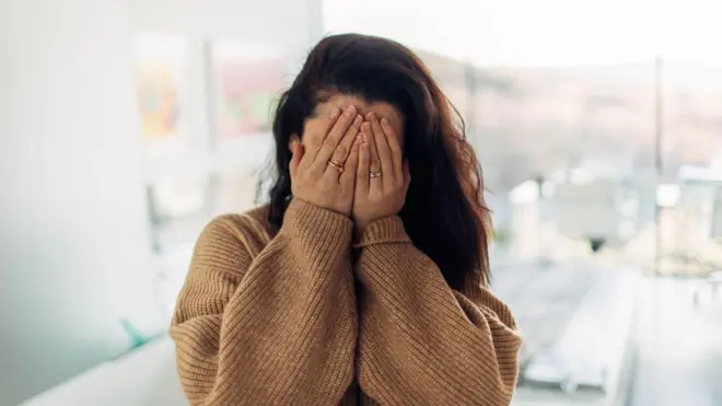 سيدة تغطي وجهها بيديها