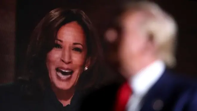 کامالا هریس با تصویر محو دونالد ترامپ پشت سر او