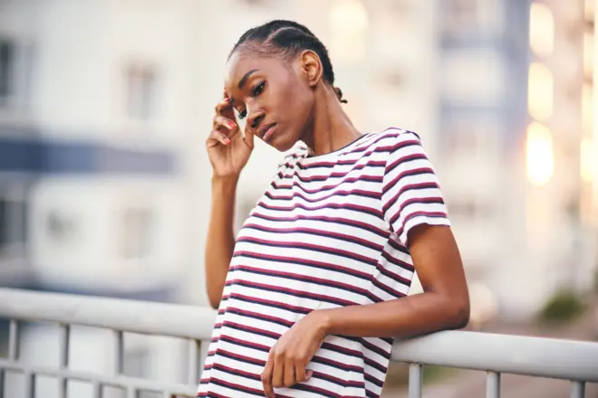 Femme avec les yeux fermés et la main sur le front en signe de plainte. 