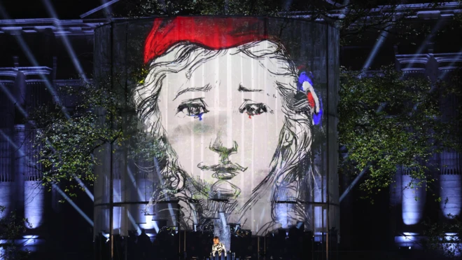 Изображение лица в красном берете на фоне стены,где также видны цвета французского флага, в день памяти о жертвах нападений в Париже 13 ноября 2015 года.