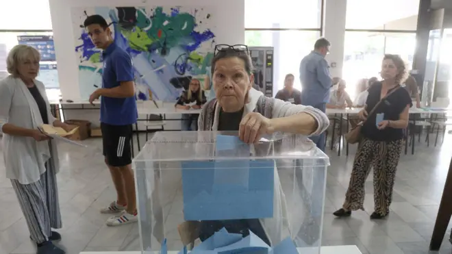 Starija žena ubacuje glasački listić u plastičnu kutiju