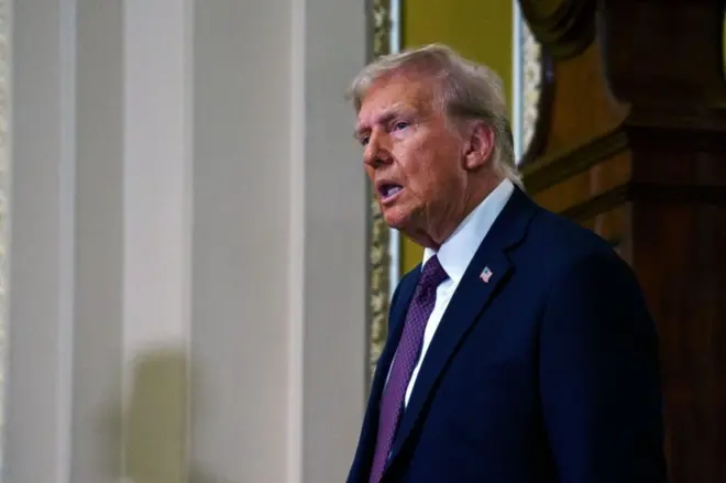 دونالد ترامب مرتدياً بدلة رسمية كحلية اللون، وربطة عنق بلونين كحلي وبنفسجي