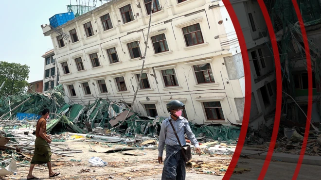 Two people walk past a large white building that is partially collapsed and leaning dangerously to one side in Mandalay