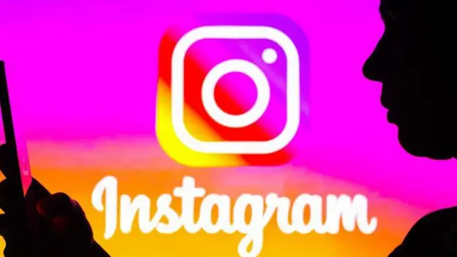 Instagram logosu önünde cep telefonuna bakan bir kişi 