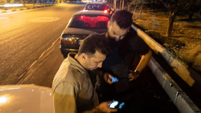 دو نفر در صف بنزین به گوشی‌هایشان نگاه می‌کنند