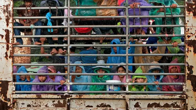 မိုးကာအပါး ရောင်စုံဝတ်ထားပြီး ကားပေါ်လိုက်စီးလာတဲ့ အရွယ်စုံ အမျိုးသား အမျိုးသမီးတွေ 