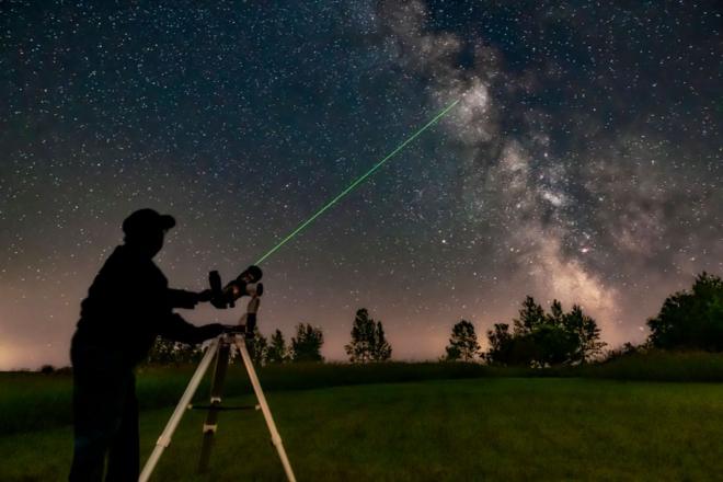 Foto de homem mexendo em um telescópio com laser