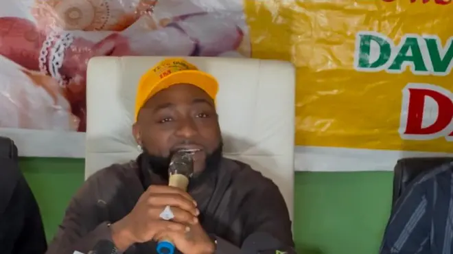 Davido wọ asọ toke tilẹ alawọ dudu, o de fila alawọ yẹlo ti ẹgbẹ Accord, o fi yẹri si eti, o si mu ẹrọ amohunbugbẹmi lọwọ