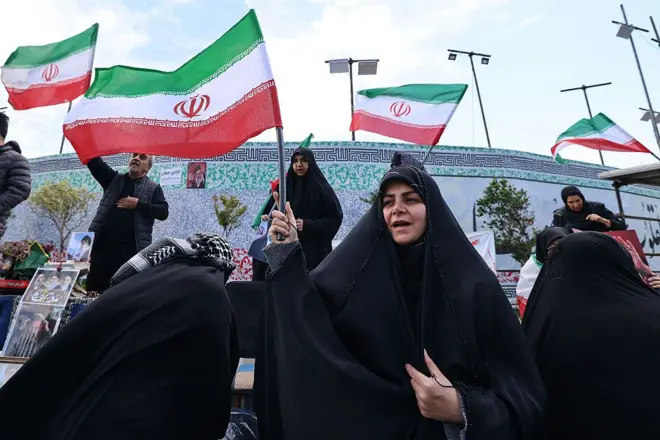 Mujeres iraníes ondean banderas nacionales mientras la gente se reúne en la Plaza de la Revolución de Teherán después de que Estados Unidos e Irán acordaran un alto el fuego de dos semanas.