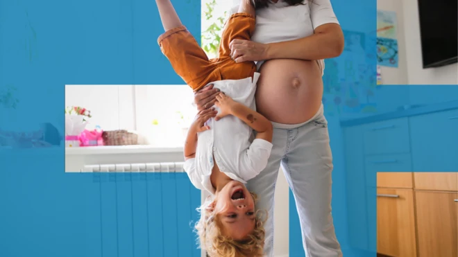 Trudna žena drži nasmejano dete za noge, a ono je okrenuto naopačke