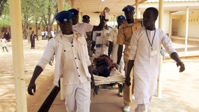 Awọn oṣiṣẹ eleto ilera to wọ aṣọ funfun n gbe alailera lọ sibi kan nile iwosan 