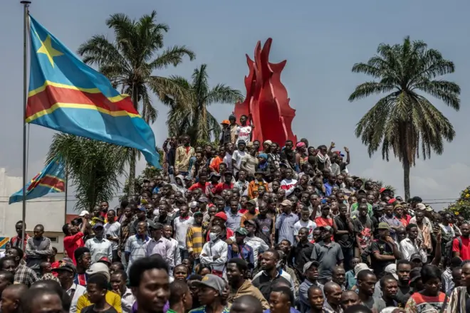 Des habitants grimpent sur un monument entouré de drapeaux congolais après un rassemblement organisé par des groupes de la société civile en soutien au mouvement M23 et contre le gouvernement central congolais à Bukavu le 22 février 2025.