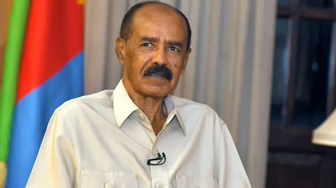 ካኪ ዝተከደነን ባንዴራ ኣብ የማናይ ጎኒ ዝገበረን ኢሳይያስ ኣፈወርቂ ቃለመሕትት እናገበረ