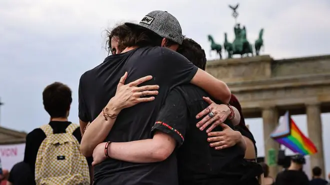 Un grupo de jóvenes se abraza ante la puerta de Branderburgo.