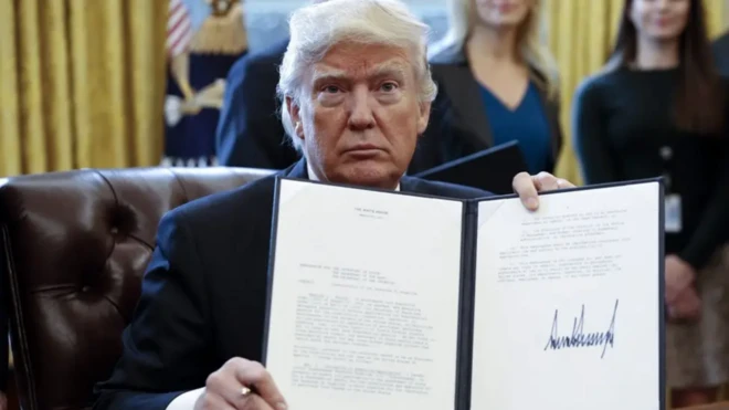 US President Donald Trump displays one of five executive orders he signed related to the oil pipeline industry in the oval office of the White House in Washington, DC, USA, 24 January 2017