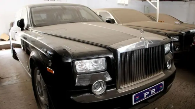 Une Rolls Royce noire garée dans un garage et couverte de poussière