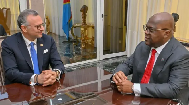 Massad Boulos, umujyanama mukuru wa Perezida w'Amerika Donald Trump kuri Afurika, i Kinshasa, muri RDC, mu kiganiro na Perezida Félix Tshisekedi. Bombi bicaye ku ntebe, bambaye kositimu, ibiganza biri ku meza. Ibendera rya RDC riraboneka kuri iyi foto yo ku wa kane, ku itariki ya 3 Mata (4) mu mwaka wa 2025. 