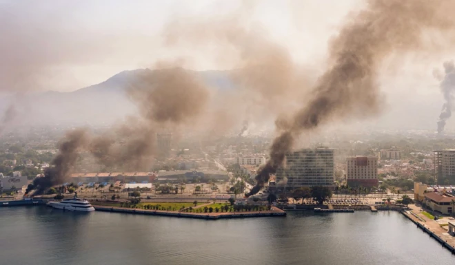 Lüks bir liman kentinden dumanlar yükseliyor. Görüntüde çok lüks bir yat da var.