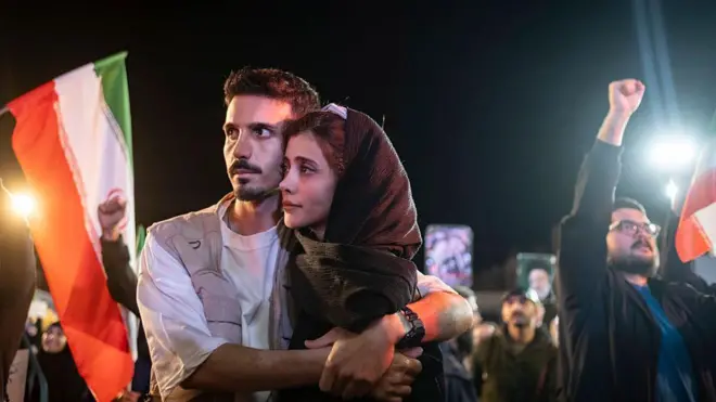 İran hükümeti yanlısı bir gösteride sloganlar atanlar arasında genç bir İranlı çift birbirine sarılıyor.