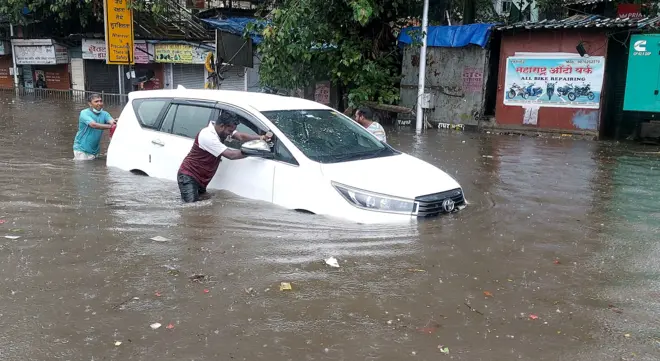 तुंबलेल्या मुंबईच्या रस्त्यावरून माणसं गाडी ओढून नेताना